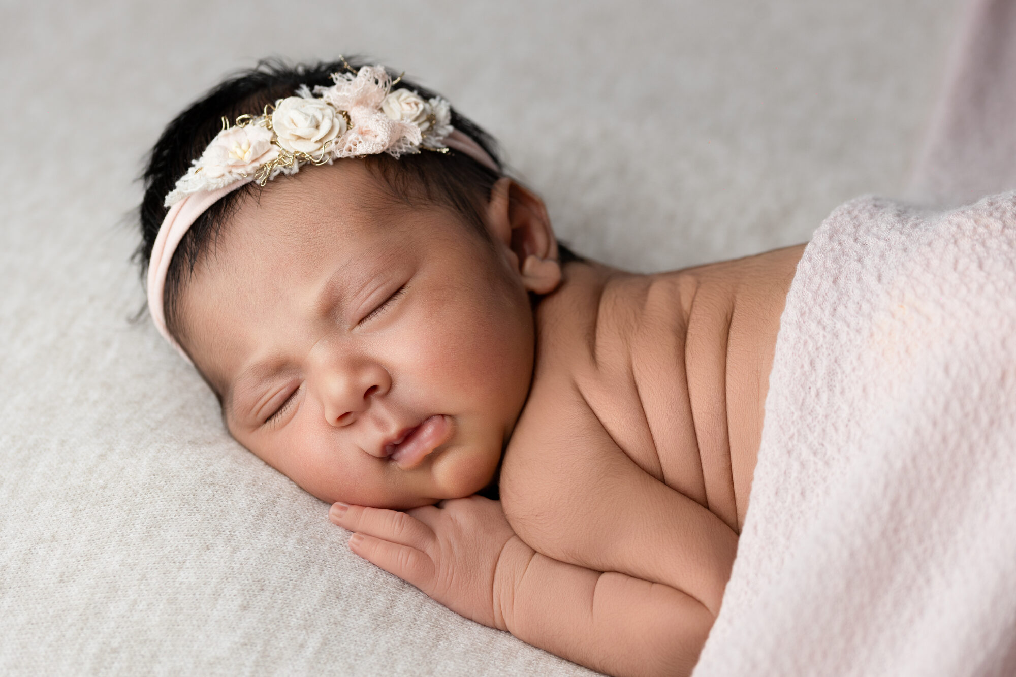 Nouveau-né endormi avec bandeau fleuri, séance naissance dans les Yvelines