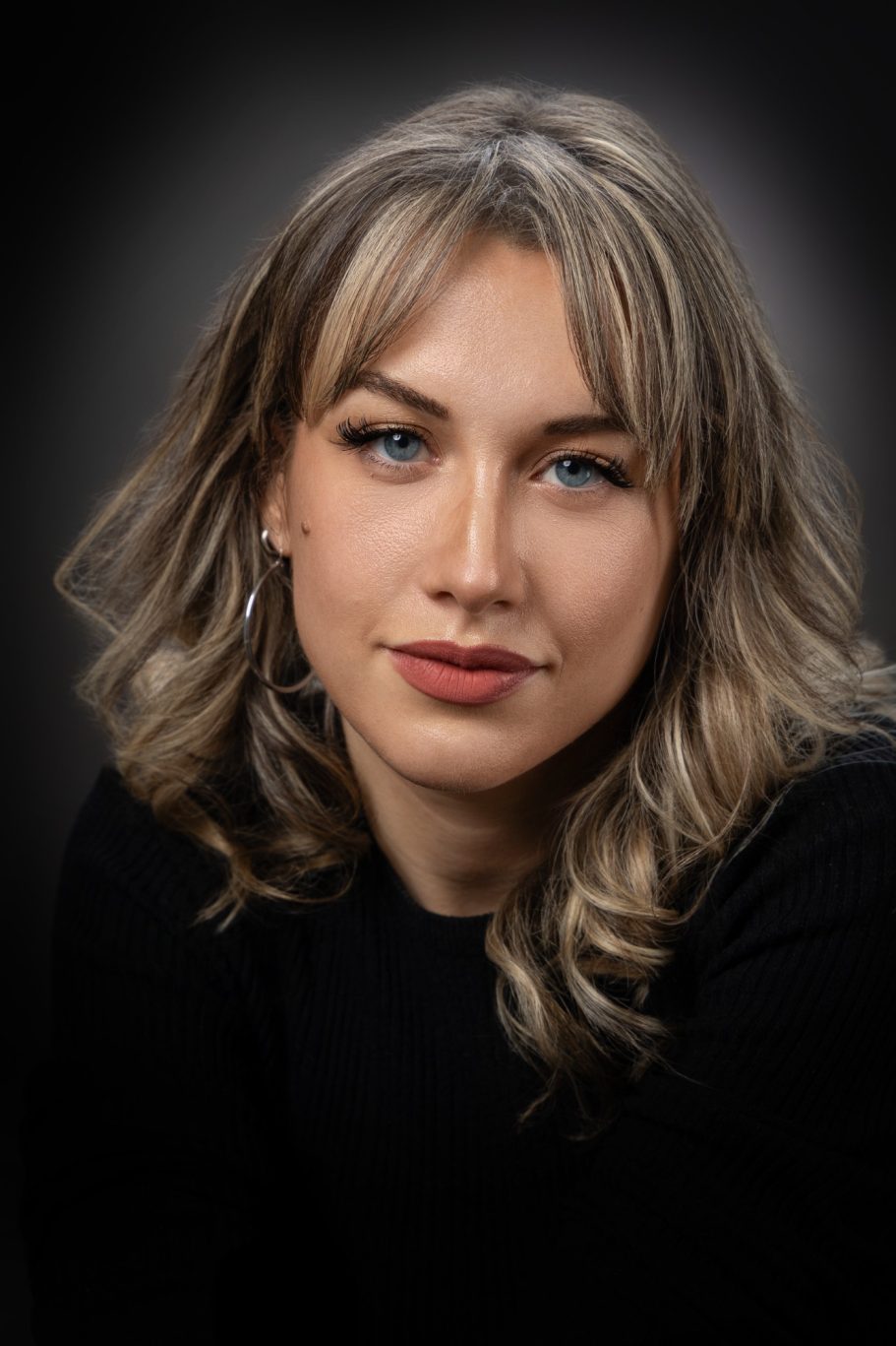 Portraits Portrait d'une femme aux cheveux blonds, avec un regard expressif sur fond sombre.