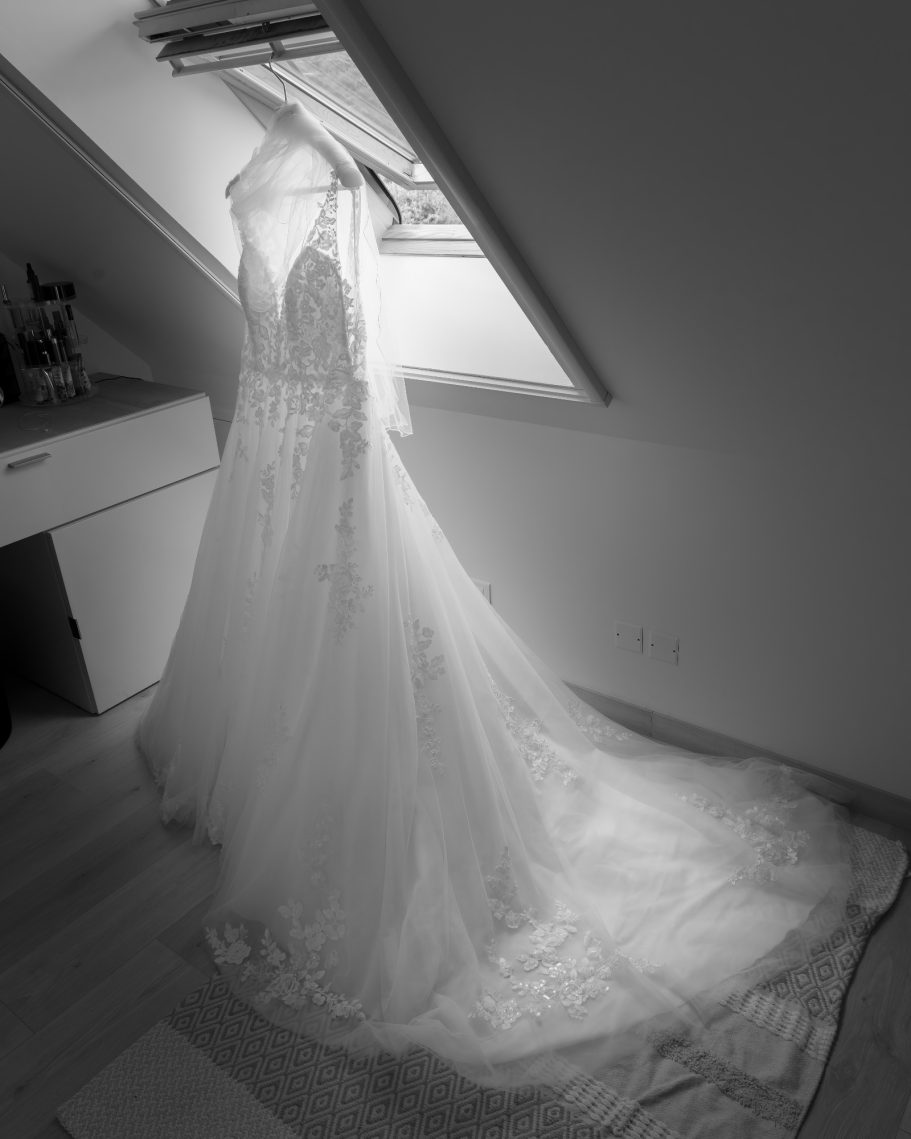 Mariage Robe de mariée élégante suspendue près d'une fenêtre, lumière douce illuminant le tissu.